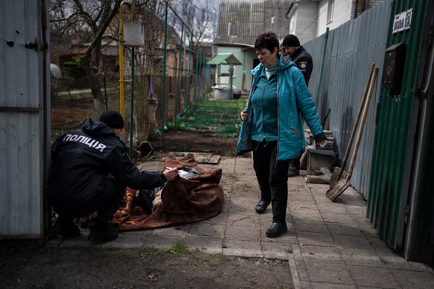  A policeman examines the corpse of a man killed during the war with Russia in Bucha, in the outskirts of Kyiv, Ukraine, Monday, April 11, 2022. (AP Photo/Rodrigo Abd) 