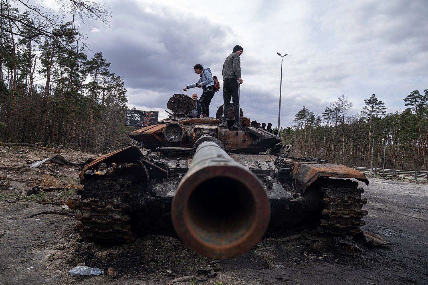  Local residents stand atop of a Russian tank damaged during fightings between Russian and Ukrainian forces in the outskirts of Kyiv, Ukraine, Monday, April 11, 2022. (AP Photo/Evgeniy Maloletka) 