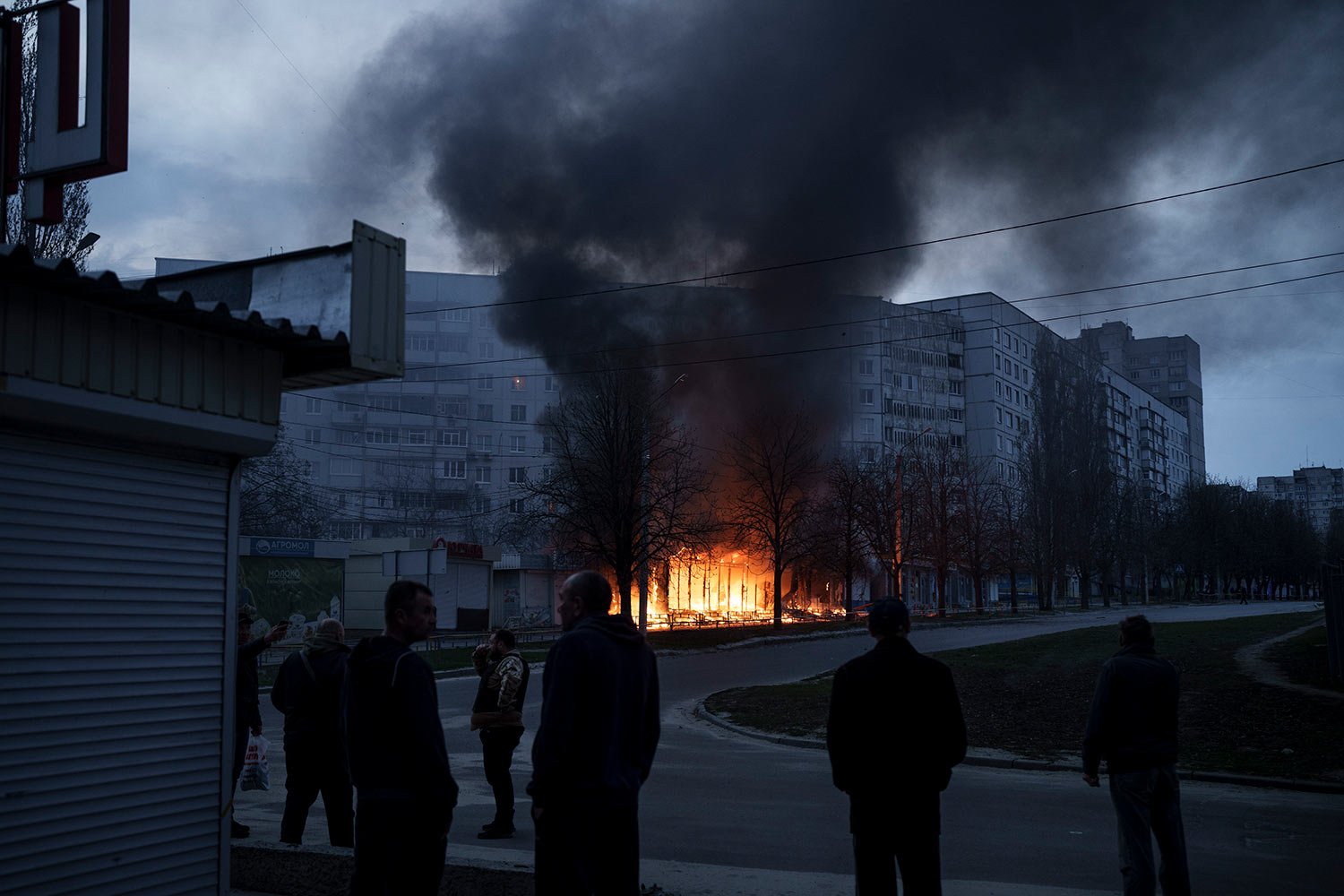  Residents stand outside their apartments as shops burn after a Russian attack in Kharkiv, Ukraine, Monday, April 11, 2022. (AP Photo/Felipe Dana) 
