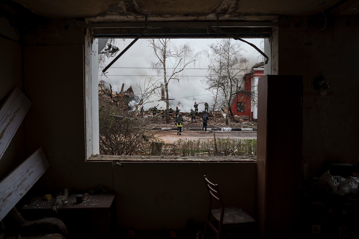  Firefighters are seen through the destroyed window of an apartment as they work to extinguish a fire after a Russian attack in Kharkiv, Ukraine, Tuesday, April 12, 2022. (AP Photo/Felipe Dana) 