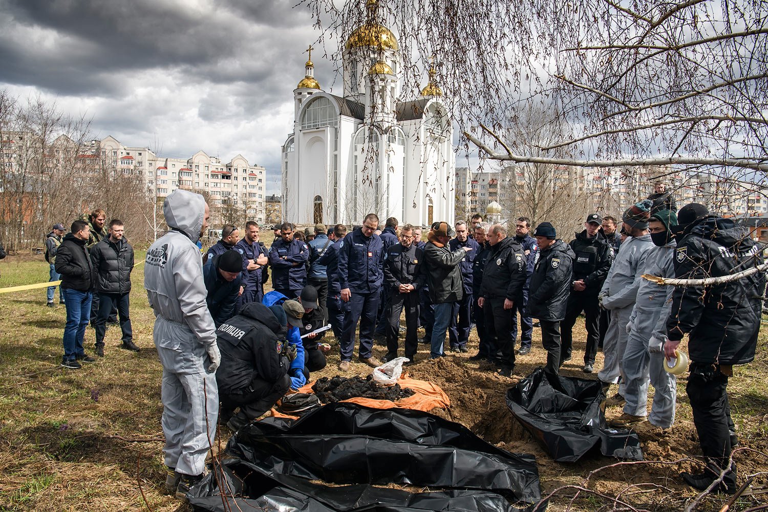  French forensics investigators, who arrived to Ukraine for the investigation of war crimes amid Russia's invasion, stand next to a mass grave in the town of Bucha, in Kyiv region, Ukraine, Tuesday, April 12, 2022. (AP Photo/Wladyslaw Musiienko) 