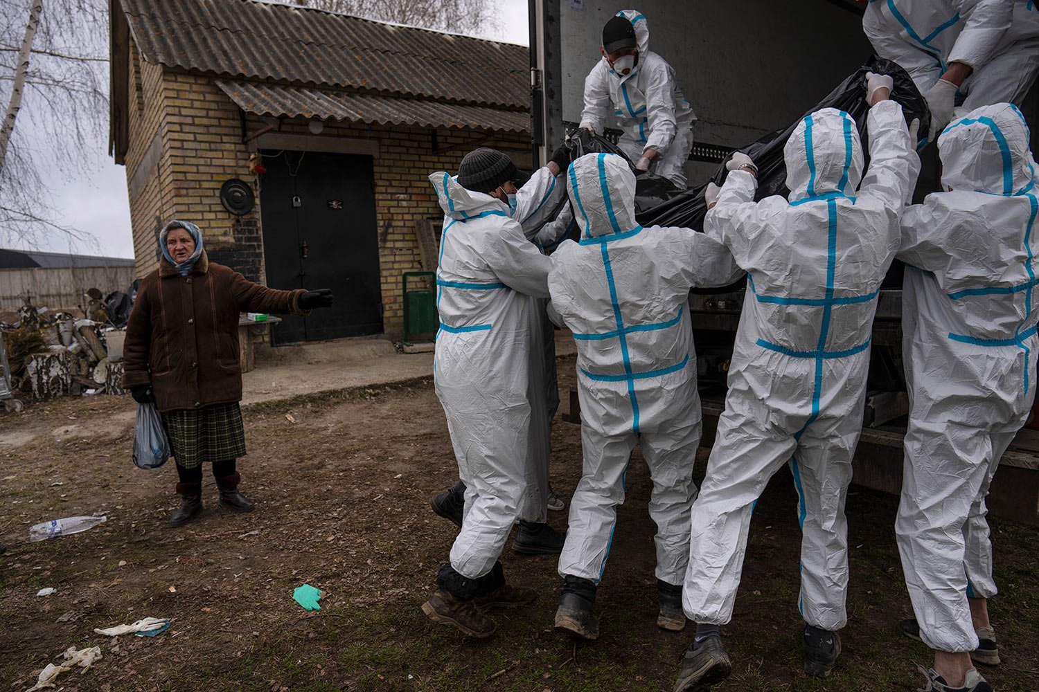  Nadiya Trubchaninova, 70, left, stands next to volunteers while loading a plastic bag that contains the body of a civilian killed by Russian soldiers into a truck, in Bucha, on the outskirts of Kyiv, Ukraine, Tuesday, April 12, 2022. (AP Photo/Rodri