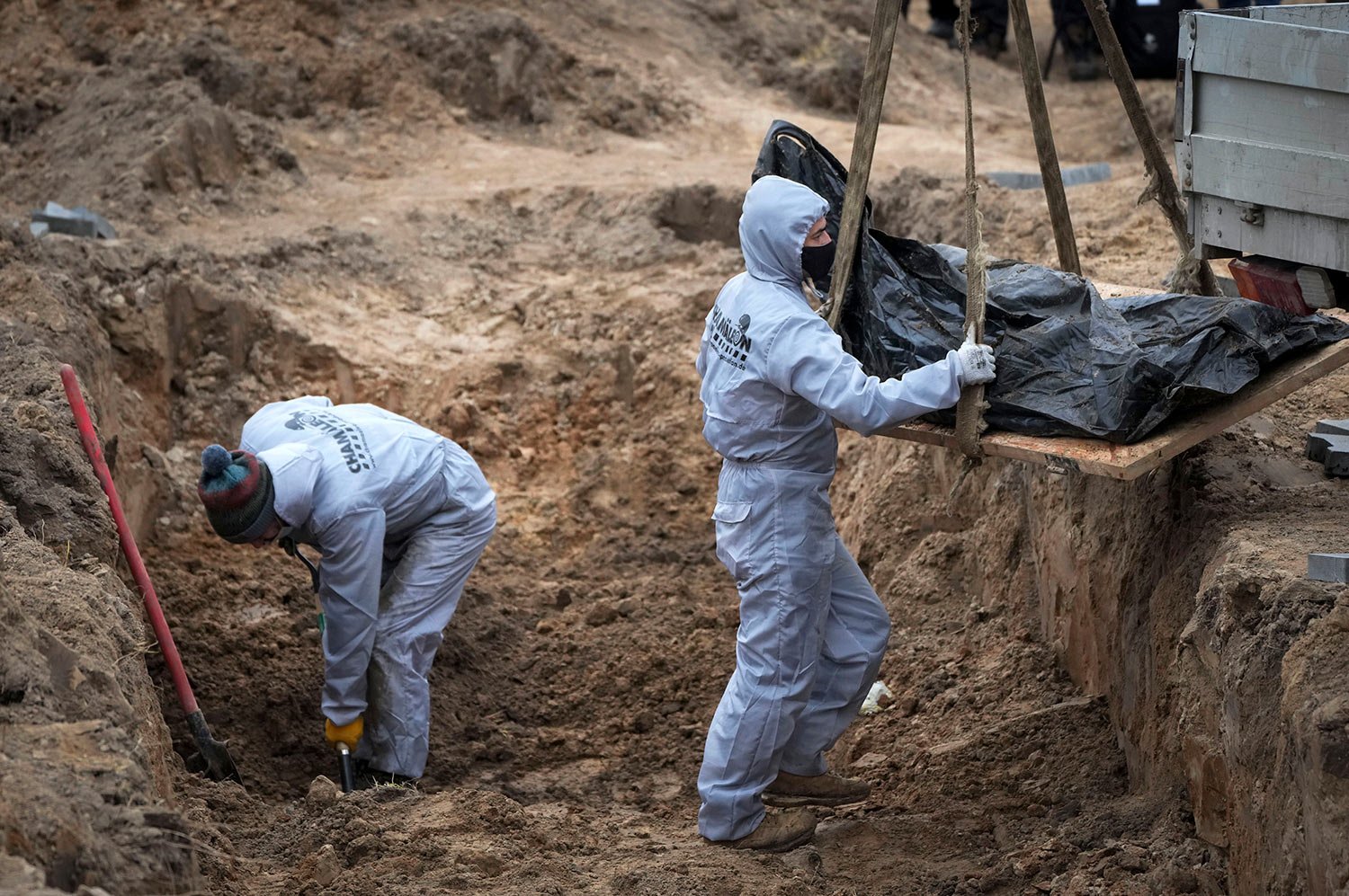  Men wearing protective gear exhume the bodies of civilians killed during the Russian occupation in Bucha, on the outskirts of Kyiv, Ukraine, Wednesday, April 13, 2022. (AP Photo/Efrem Lukatsky) 