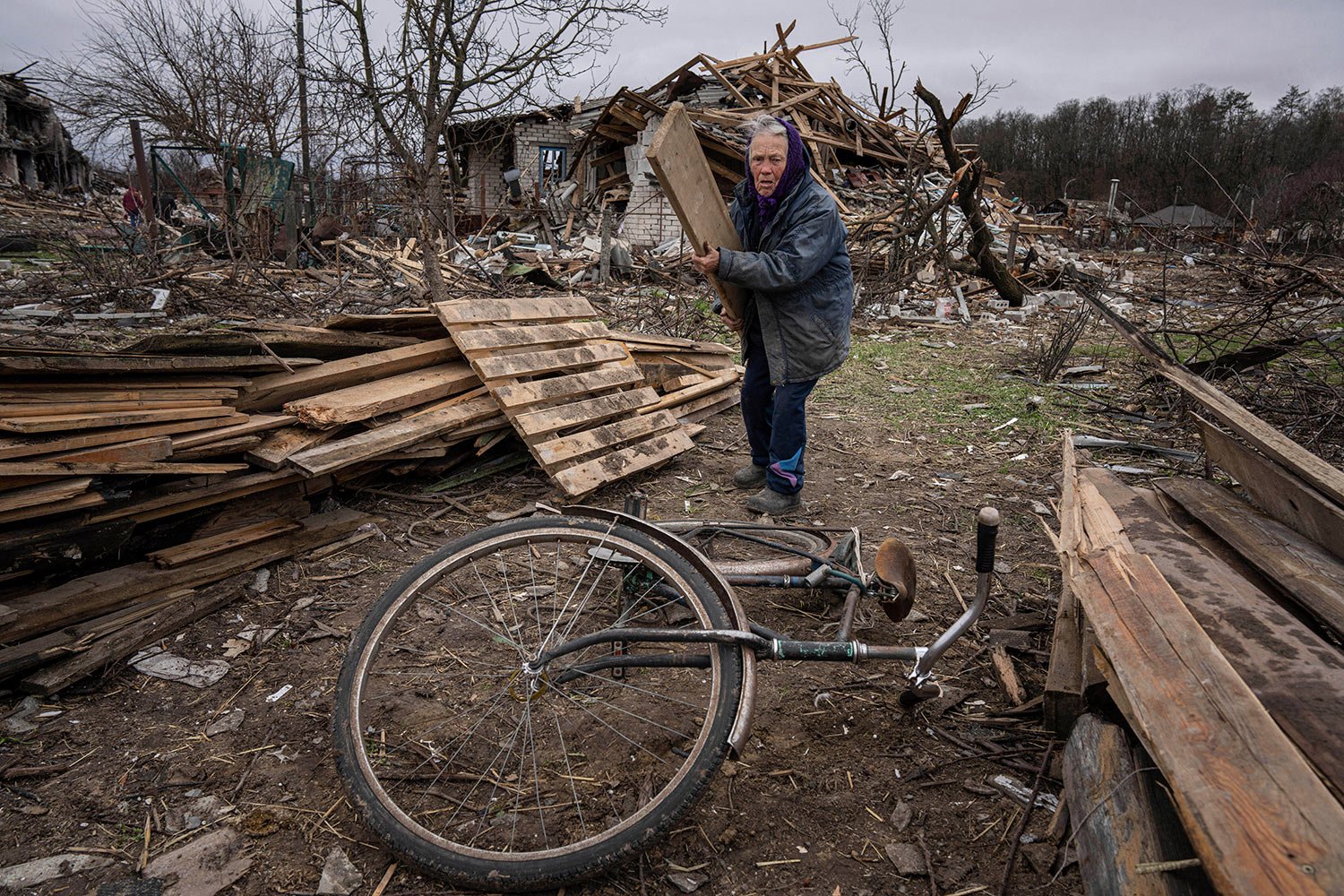  A woman collects wooden planks in a street destroyed by shelling in Chernihiv, Ukraine, Wednesday, April 13, 2022. (AP Photo/Evgeniy Maloletka) 