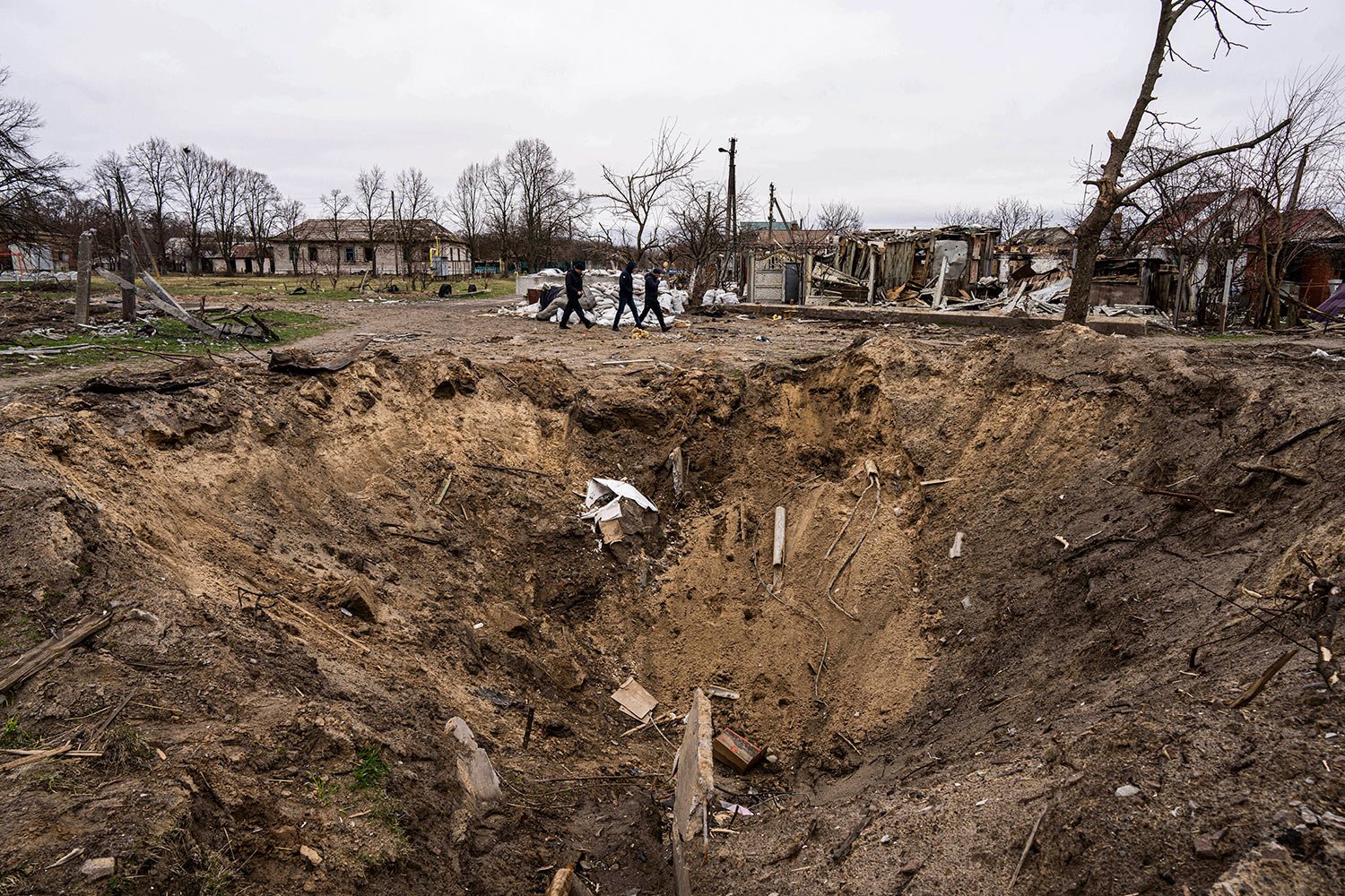  People walk past a crater from an explosion in Chernihiv, Ukraine, Wednesday, April 13, 2022. (AP Photo/Evgeniy Maloletka) 