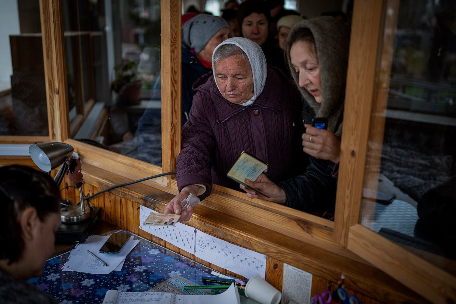  Ukrainian women show their ID inside a church to receive humanitarian aid donated by European Union in Bucha, in the outskirts of Kyiv, on Tuesday, April 19, 2022. (AP Photo/Emilio Morenatti) 