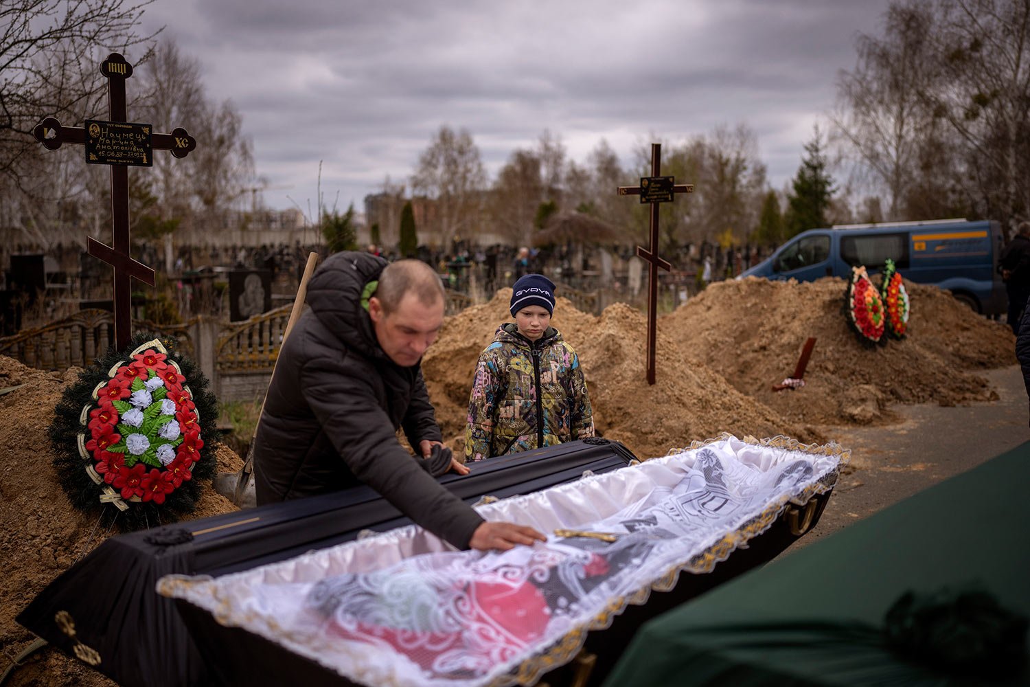  Vova, 10, looks at the body of his mother, Maryna, lying in a coffin as his father, Ivan Drahun, prays during her funeral in Bucha, on the outskirts of Kyiv, Ukraine, on Wednesday, April 20, 2022. Vova's mother died while they sheltered in a cold ba