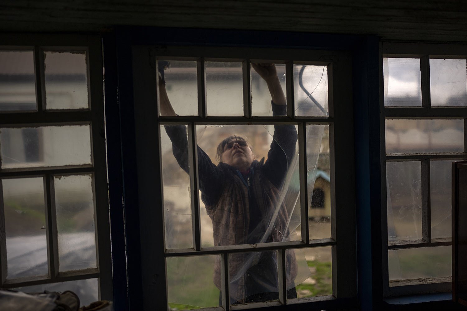  Tetyana Boikiv, 52, puts plastic sheeting on the windows of her home that were broken by explosions during the Russian invasion of her neighborhood in Ozera village near Bucha, Ukraine, Tuesday, April 26, 2022. Tetyana buried her husband Moroz Mykol