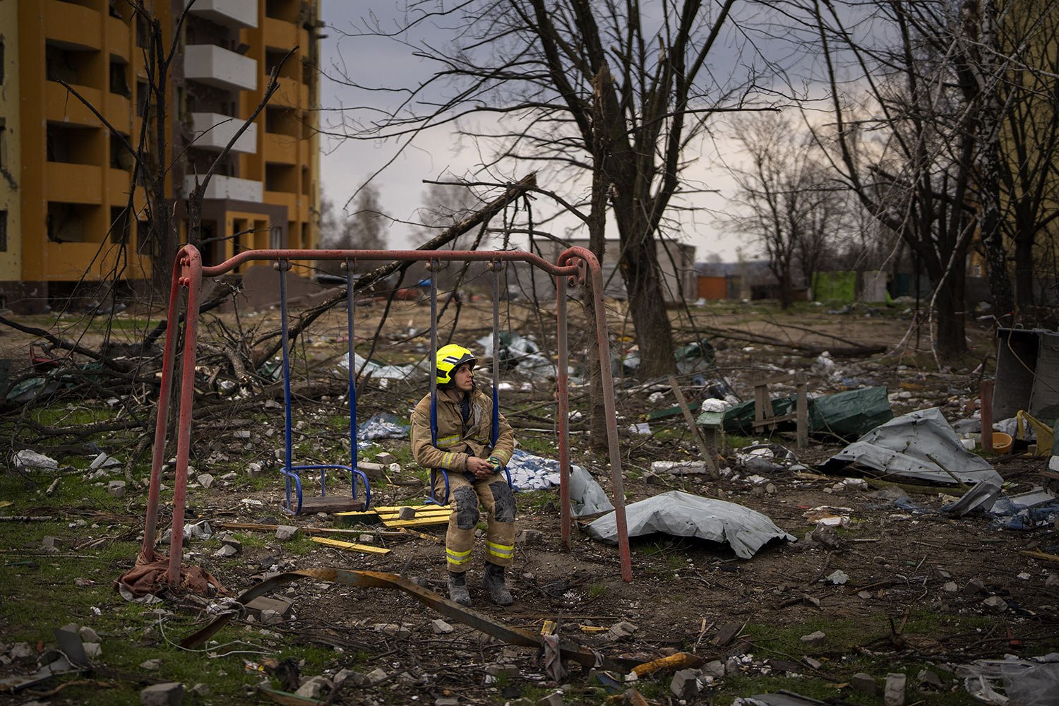  A firefighter sits on a swing next to a building destroyed by a Russian bomb in Chernihiv, Ukraine, Friday, April 22, 2022. (AP Photo/Emilio Morenatti) 