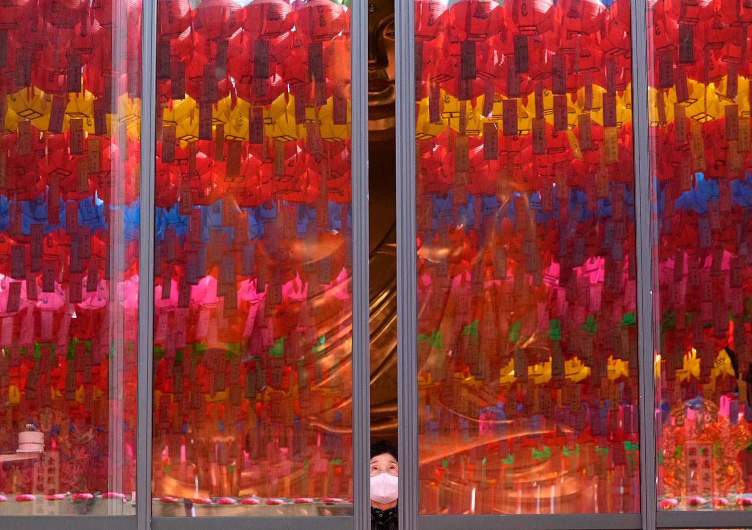  A woman wearing a face mask opens the window which reflects lanterns displayed for upcoming Buddha's birthday celebration slated for May 8, at Jogyesa temple in Seoul, South Korea, Wednesday, April 27, 2022. (AP Photo/Ahn Young-joon) 