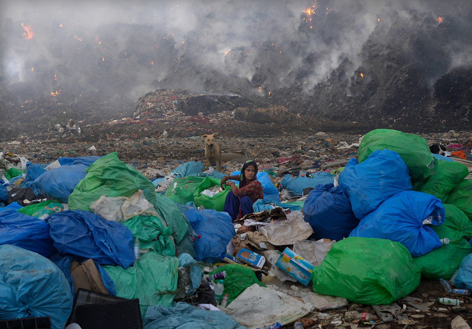 A ragpicker woman segregates items sitting at the edge during a fire at the Bhalswa landfill in New Delhi, India, Wednesday, April 27, 2022. (AP Photo/Manish Swarup) 