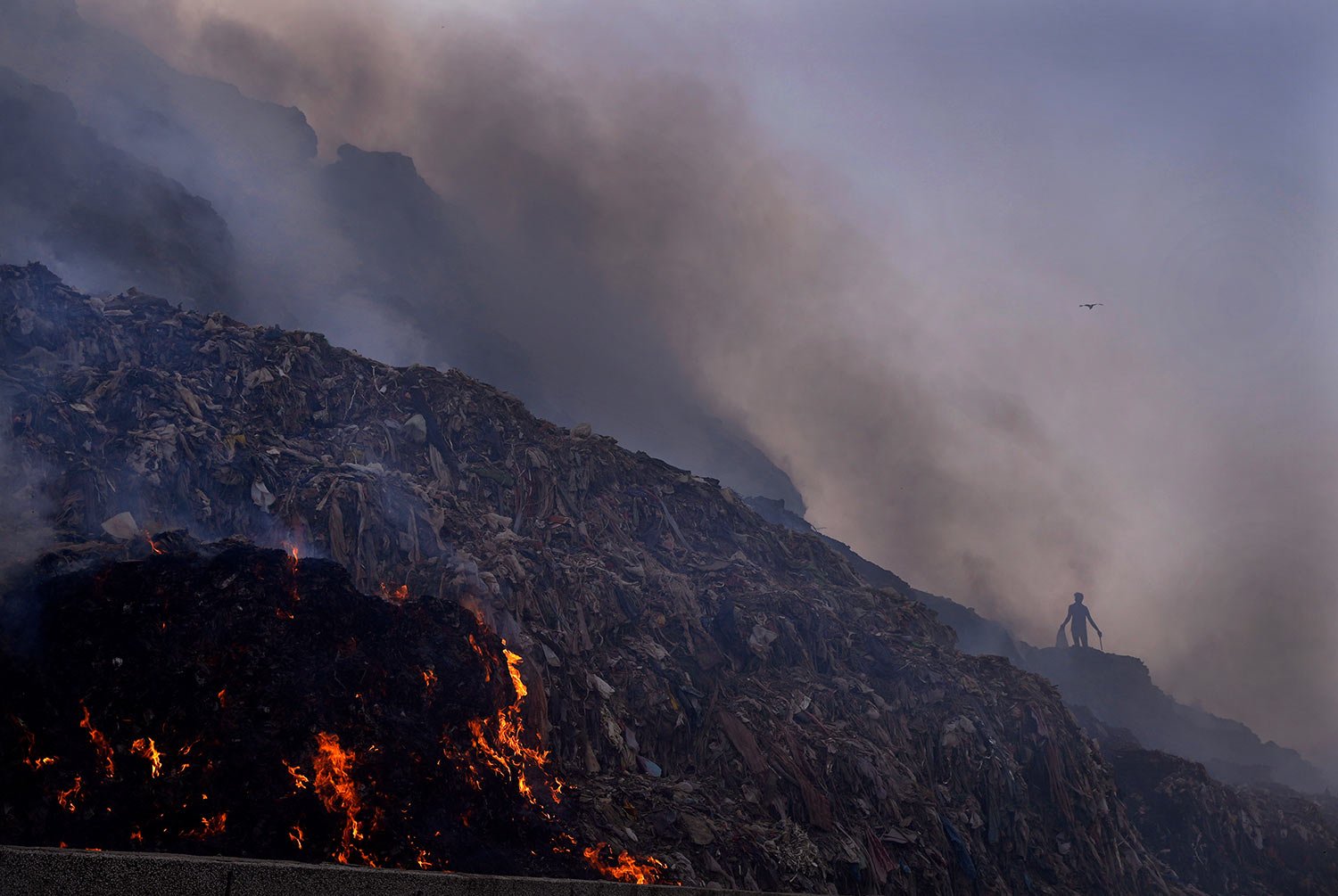  A ragpicker looks for reusable items while a fire rages at the Bhalswa landfill in New Delhi, Wednesday, April 27, 2022.  (AP Photo/Manish Swarup) 