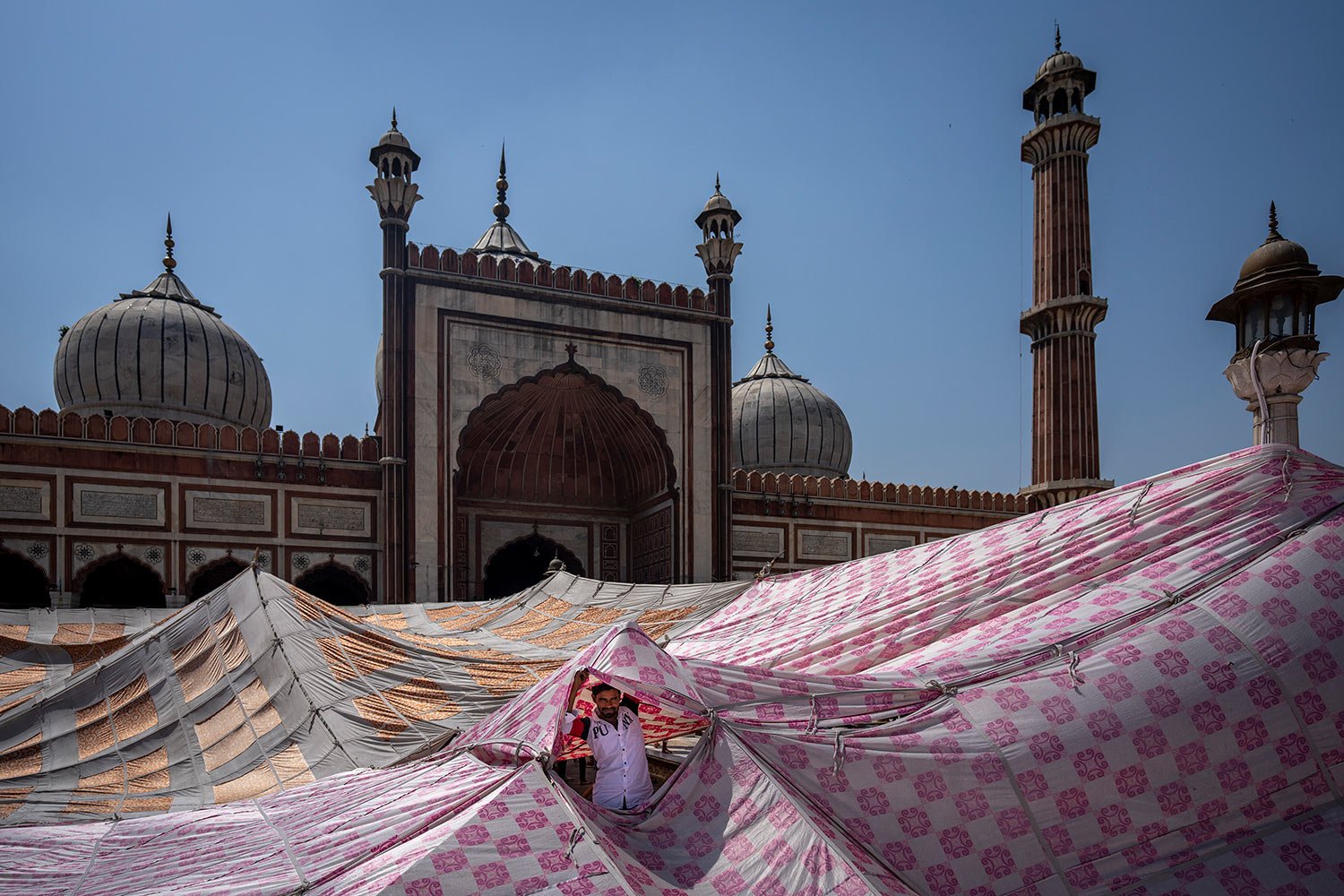  An Indian Muslim man looks through a sunshade tent erected for worshippers in the compound of Jama Masjid on the first Friday of the holy fasting month of Ramadan in New Delhi, India, Friday, April 8, 2022. (AP Photo/Altaf Qadri) 