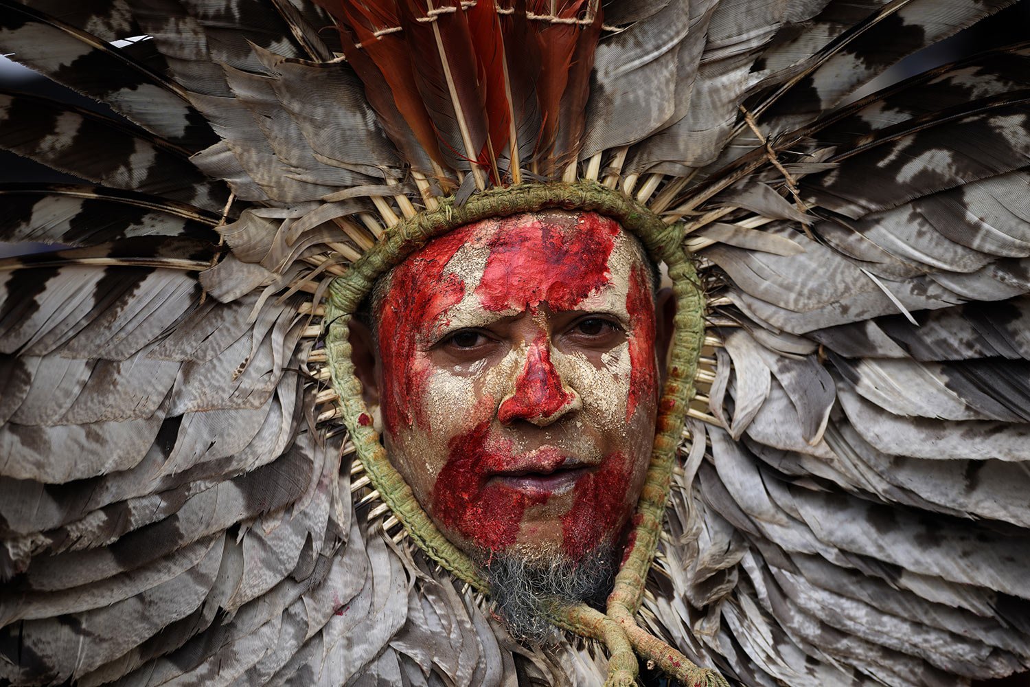  An Indigenous man, his face painted with red ink representing spilled Indigenous blood and clay representing gold, protests the increase of mining activities that are encroaching on his land, outside the Mines and Energy Ministry in Brasilia, Brazil
