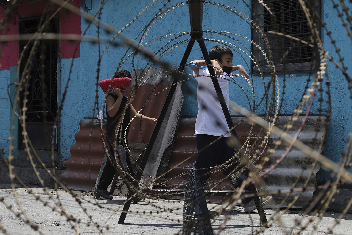  Children walk behind concertina wire as soldiers patrol the entrances of the San Jose del Pino Community in Santa Tecla, El Salvador, April 6, 2022, during a crackdown on gangs. Congress authorized prison sentences of 10 to 15 years for news media t