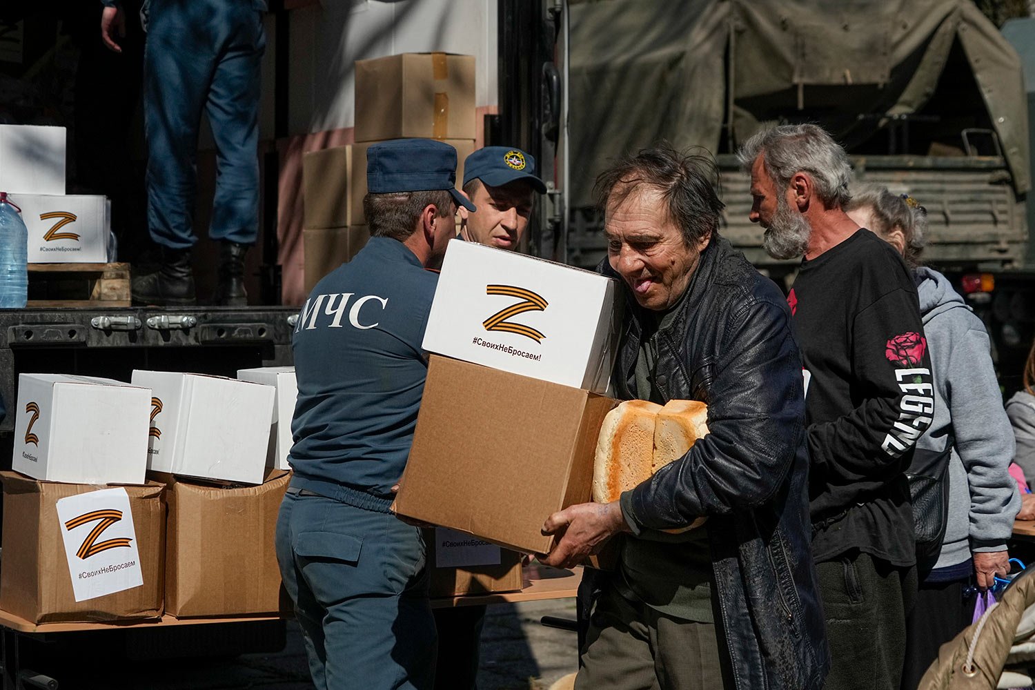  A man carries bread and boxes with the letter Z, which has become a symbol of the Russian military, and a hashtag reading "We don't abandon our own", as other local civilians gather to get humanitarian aid, bread and water distributed by Donetsk Peo