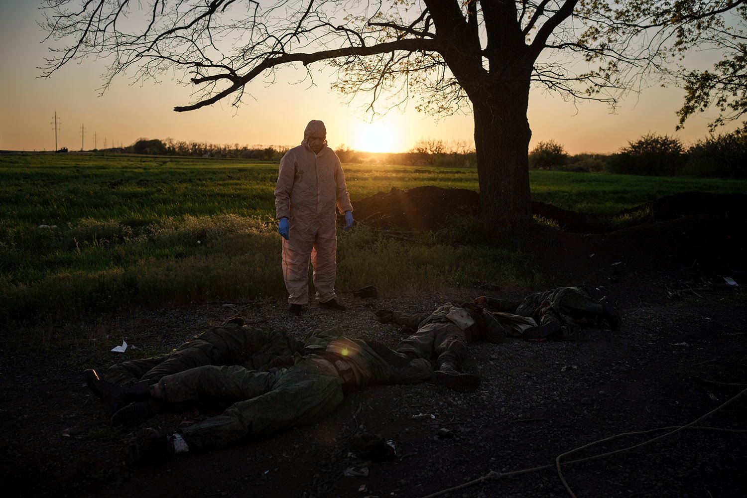  A Ukrainian emergency worker stands next to the bodies of Russian soldiers in the village of Vilkhivka, recently retaken by Ukrainian forces near Kharkiv, Ukraine, Monday, May 9, 2022. (AP Photo/Felipe Dana) 