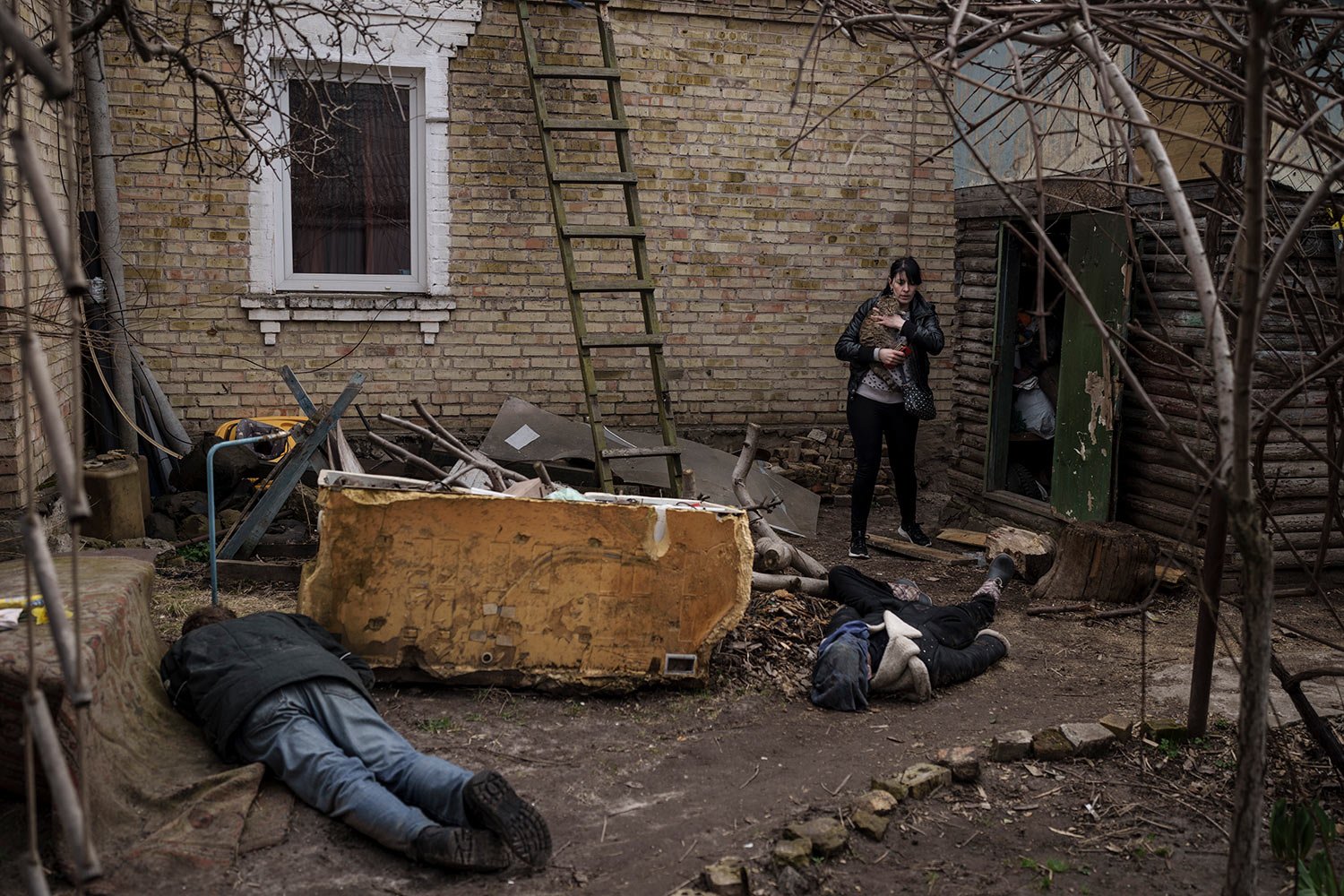  Ira Gavriluk holds her cat as she walks next to the bodies of her husband, brother and another man, who were killed outside her home in Bucha, on the outskirts of Kyiv, Ukraine, Monday, April 4, 2022. (AP Photo/Felipe Dana)  
