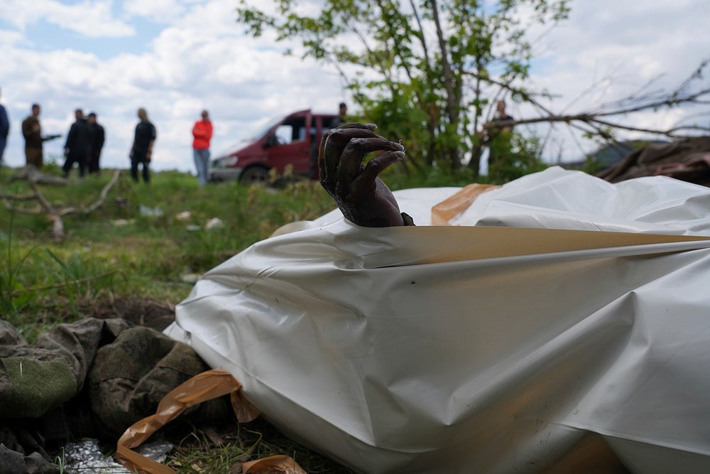  The withered hand of a dead Russian soldier pokes out of a body bag during the exhumation of killed Russian soldiers' at their former positions near the village of Malaya Rohan, on the outskirts of Kharkiv, Wednesday May 18, 2022. (AP Photo/Andrii M