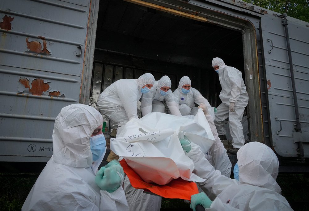  Ukrainian servicemen load bodies of Russian soldiers into a railway refrigerator carriage in Kyiv, Ukraine, Friday, May 13, 2022. (AP Photo/Efrem Lukatsky) 