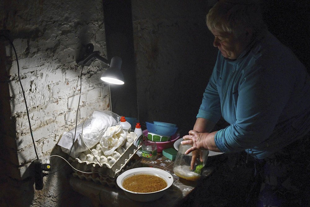  A Ukrainian woman washes dishes in the basement of a building used as bomb shelter in Soledar, Donetsk region, Ukraine, Tuesday, May 24, 2022. Those in towns and villages near the front lines hide in basements from constant shelling, struggling to s