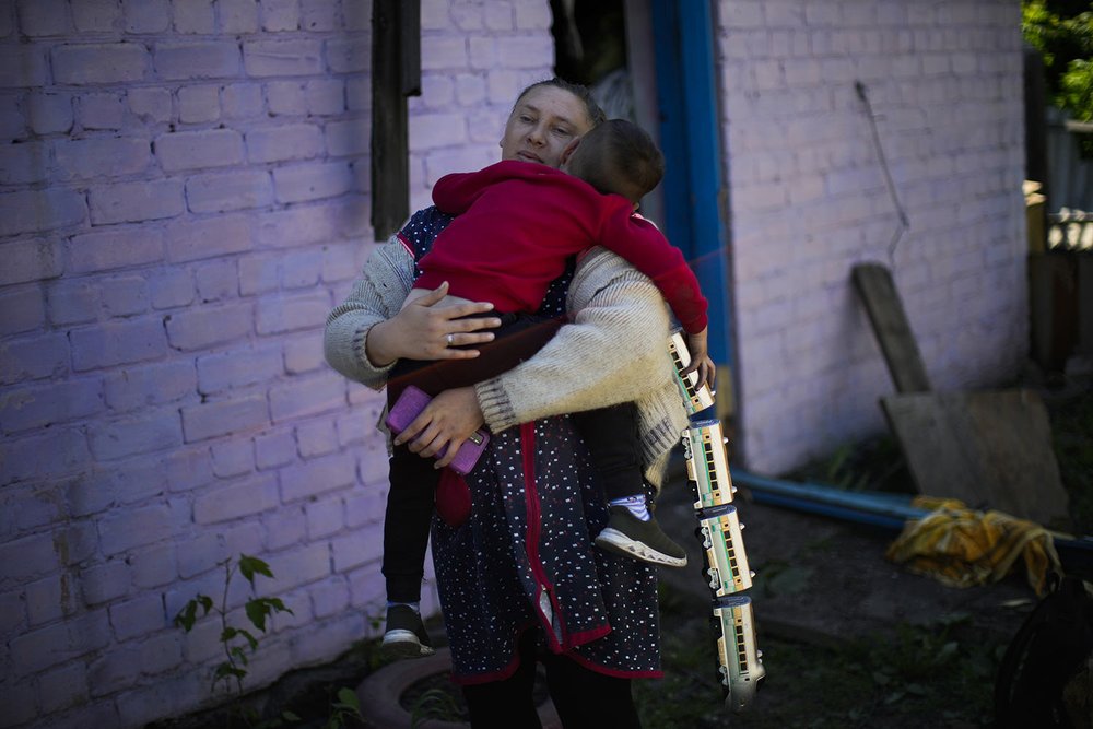  A woman holds a child outside her family's heavily damaged house after a Russian strike in Pokrovsk, eastern Ukraine, Wednesday, May 25, 2022, on the day two rockets struck the eastern Ukrainian town in the Donetsk region. (AP Photo/Francisco Seco) 