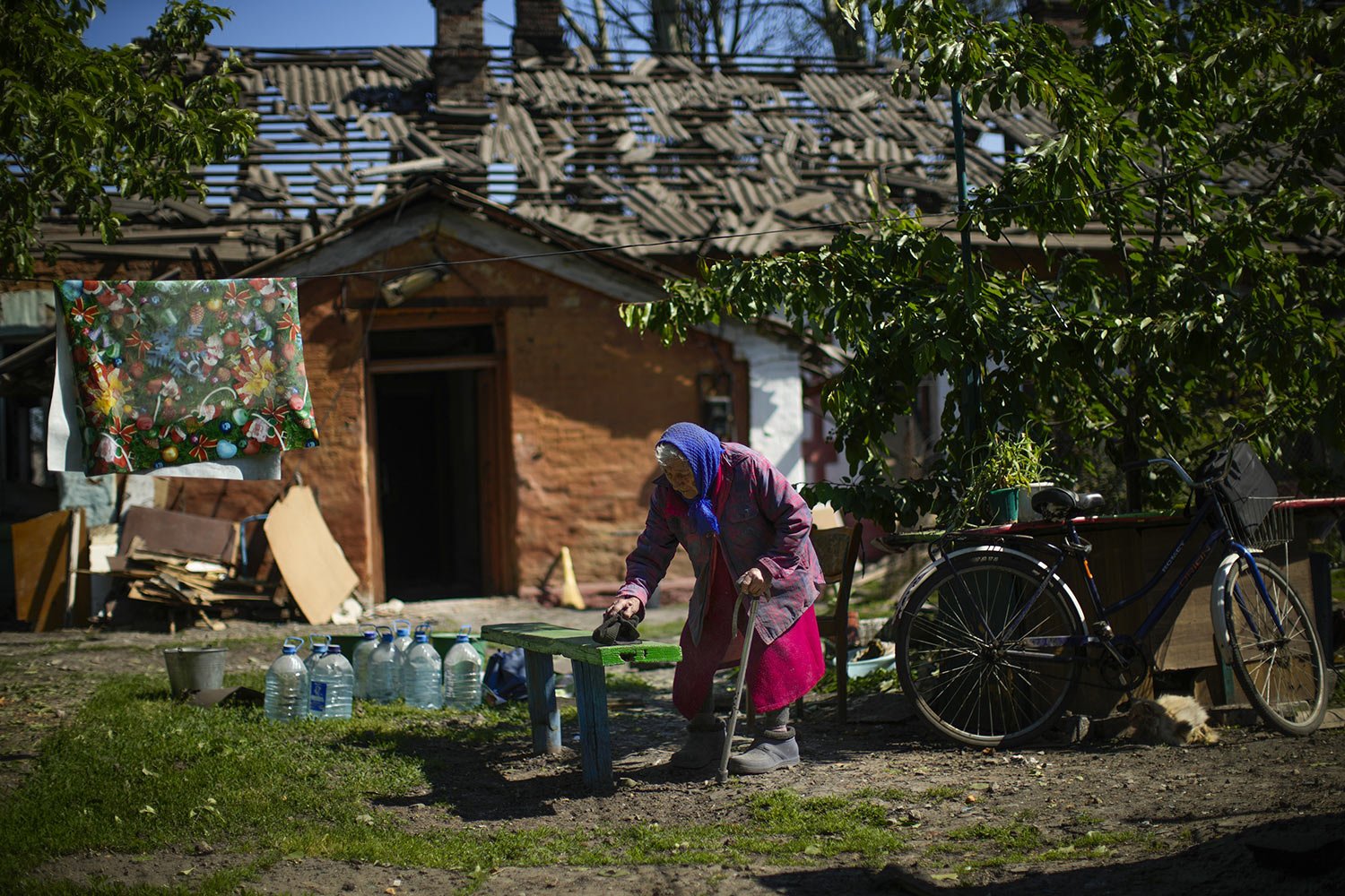  Valeria cleans the bench outside her heavily damaged house, behind, after a Russian strike in Pokrovsk, eastern Ukraine, Wednesday, May 25, 2022, after two rockets struck this town in the Donetsk region. (AP Photo/Francisco Seco) 