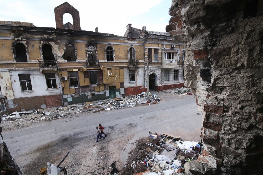  Children walk amid destroyed buildings in Mariupol which is Russian control in eastern Ukraine, Wednesday, May 25, 2022. (AP Photo) 