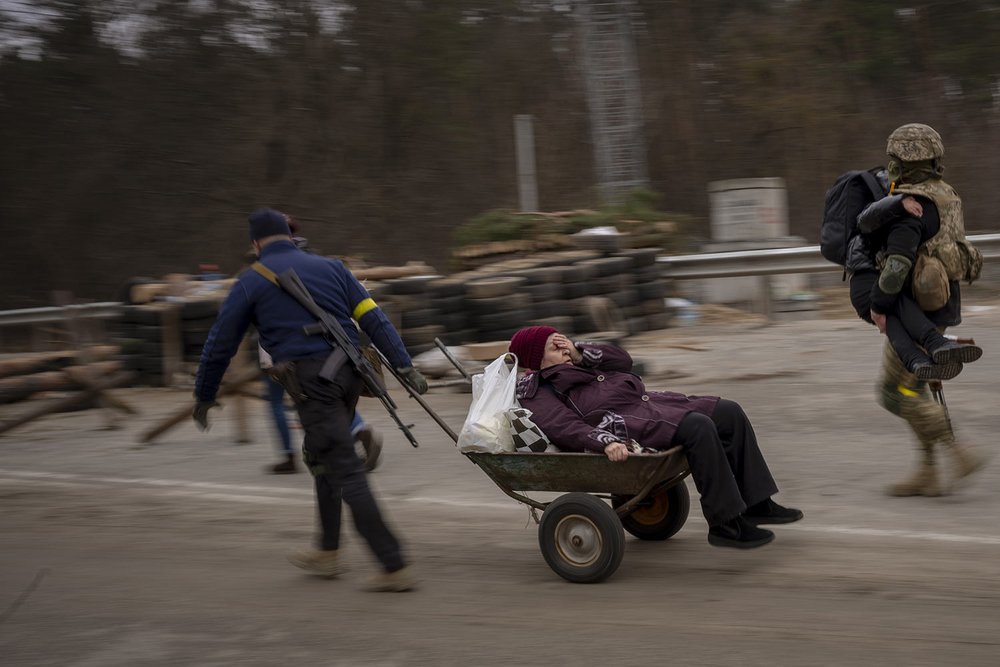  A Ukrainian soldier and a militia man help a fleeing family to cross the Irpin River on the outskirts of Kyiv, Ukraine, Saturday, March 5, 2022. (AP Photo/Emilio Morenatti) 