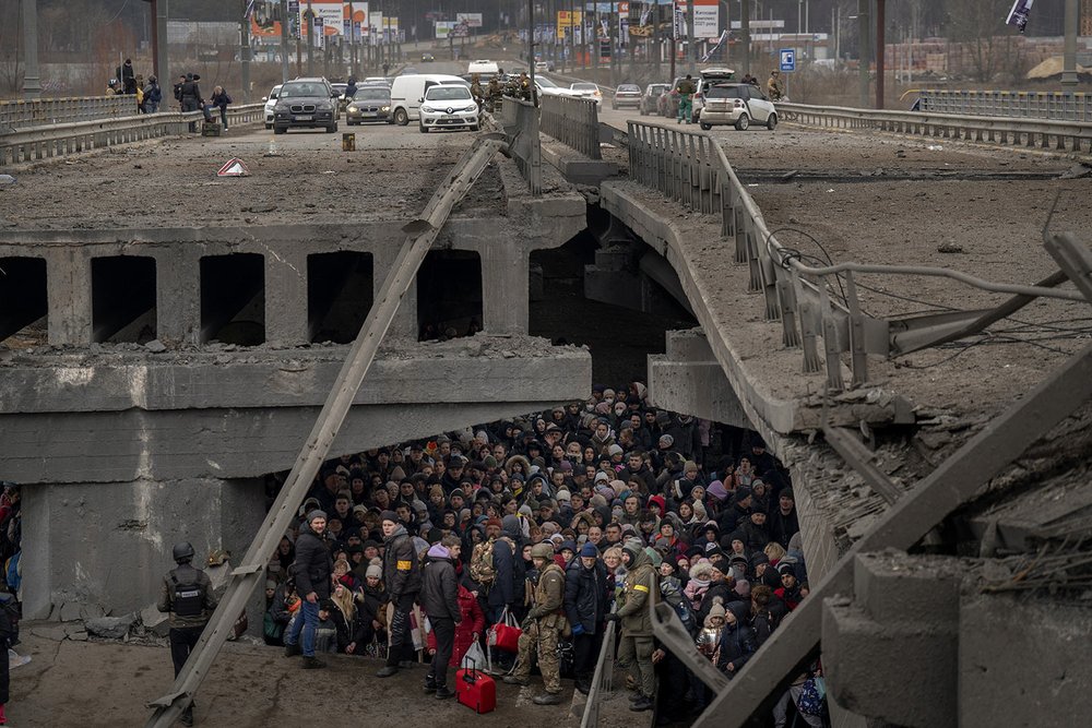  Ukrainians crowd under a destroyed bridge as they try to flee by crossing the Irpin River on the outskirts of Kyiv, Ukraine, Saturday, March 5, 2022. (AP Photo/Emilio Morenatti) 
