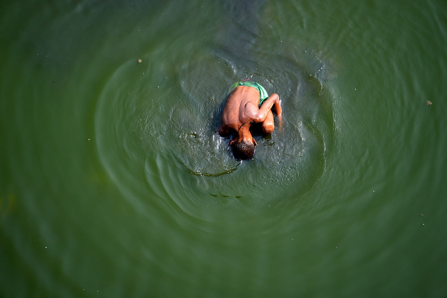  A boy searches for coins thrown by Hindu devotees in river Yamuna where water levels have reduced drastically following hot weather in New Delhi, India, Monday, May 2, 2022. (AP Photo/Manish Swarup) 