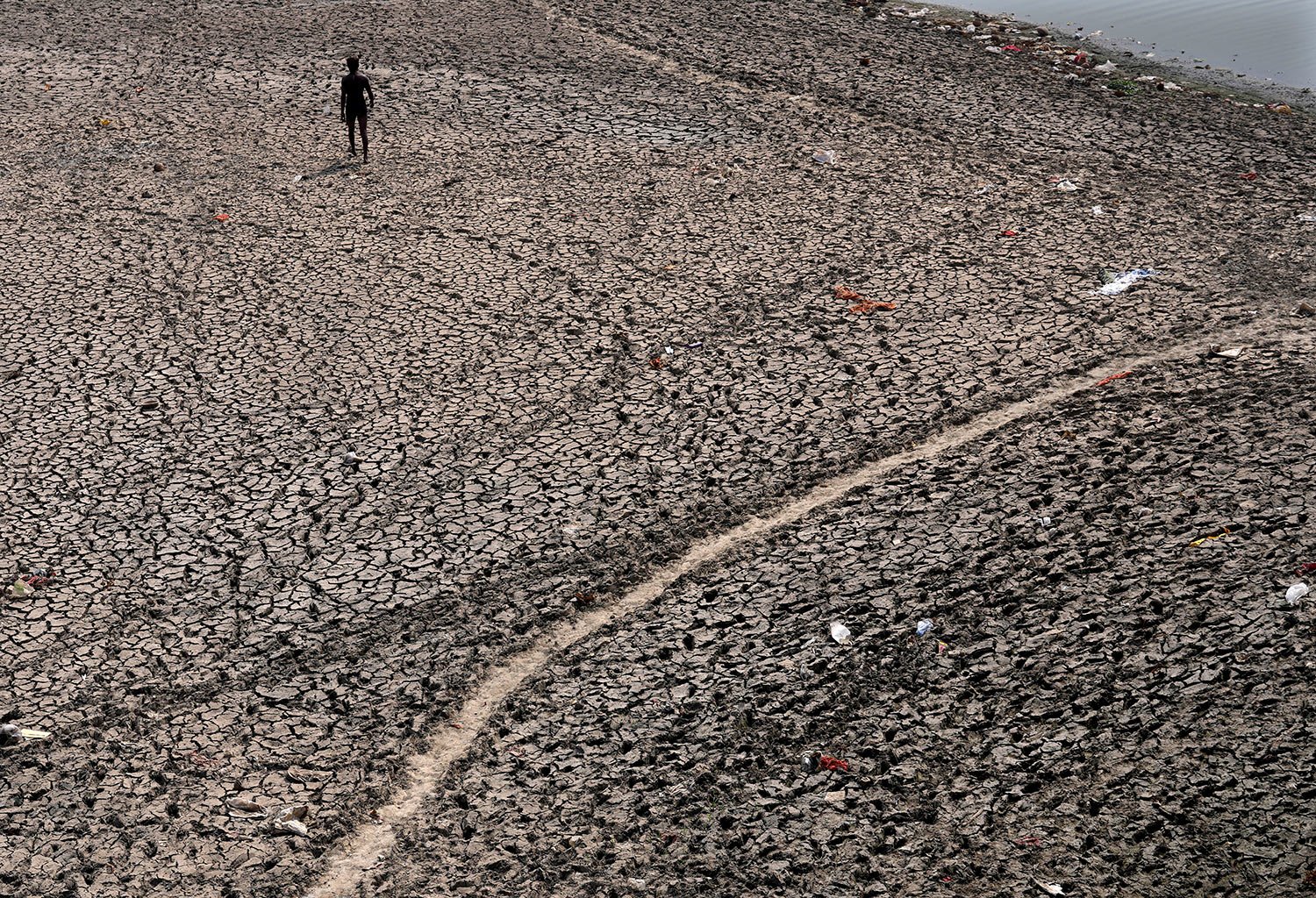  A man walks across a dried bed of river Yamuna where water levels have reduced drastically following hot weather in New Delhi, India, Monday, May 2, 2022. (AP Photo/Manish Swarup) 