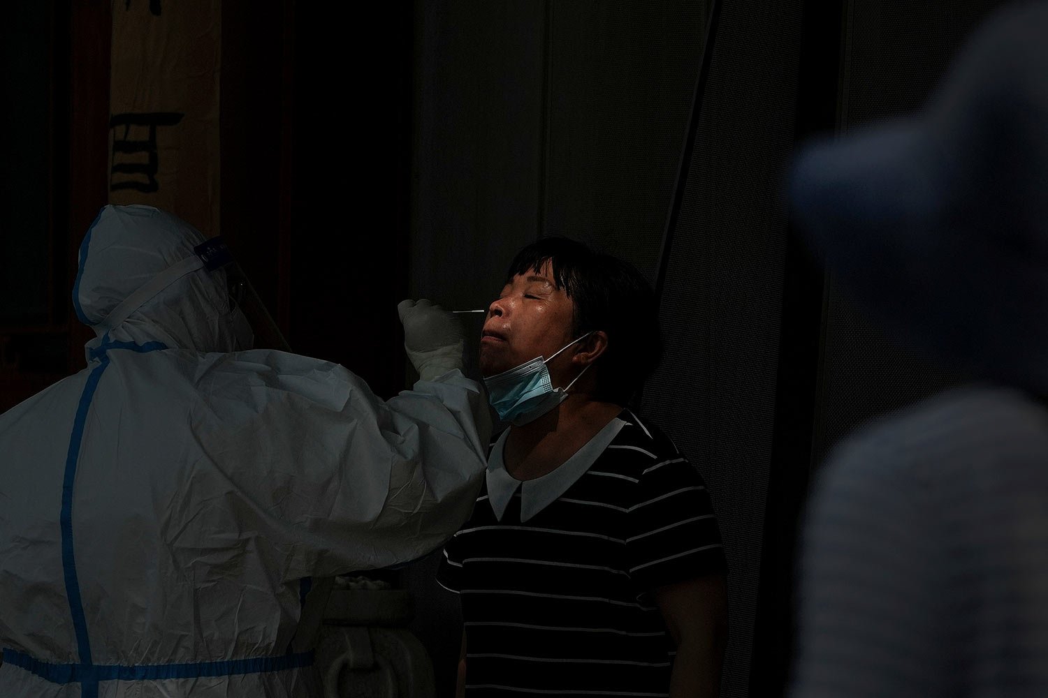  A medical worker swabs the nose of a woman who has been under home quarantine in Beijing, Tuesday, May 24, 2022. (AP Photo/Andy Wong) 