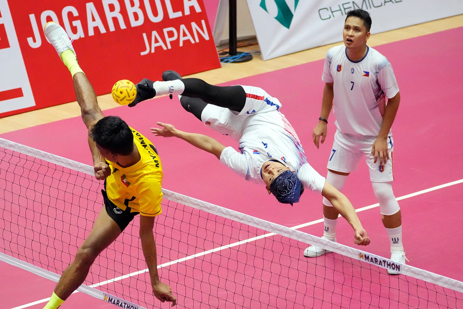  RheyJey C. Ortouste of the Philippines, center, kicks a ball against Kyaw Zin Latt of Myanmar, left, during the men's sepaktakraw regu match at the 31st Southeast Asian Games (SEA Games 31) in Hanoi, Vietnam, Tuesday, May 17, 2022. (AP Photo/Achmad 