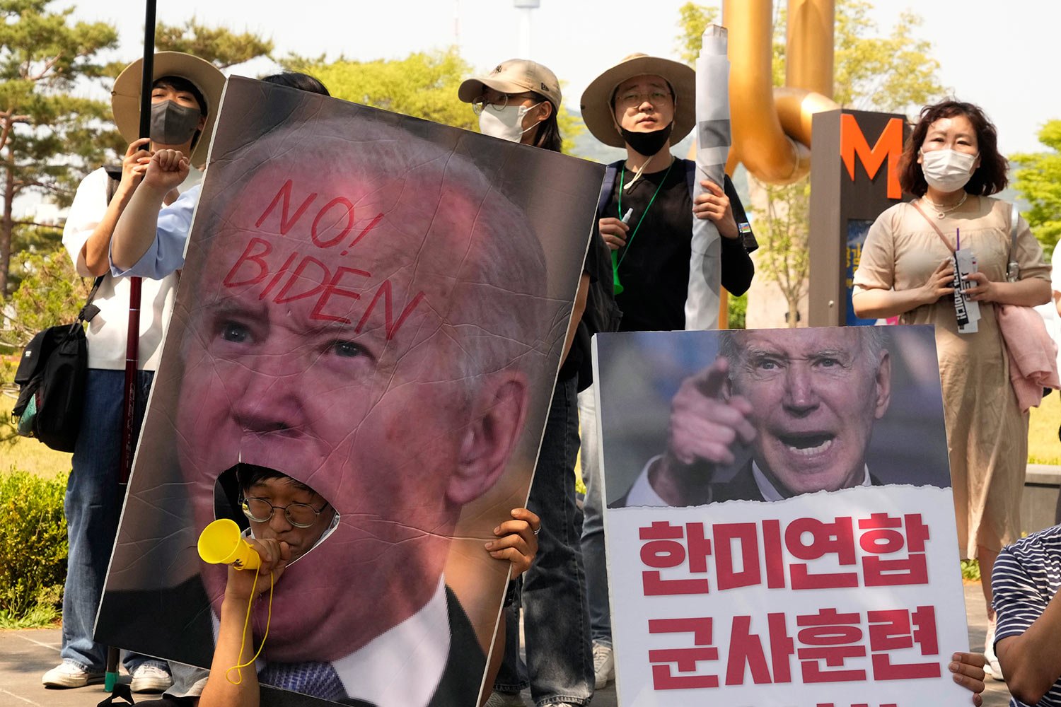  A protester blows a vuvuzela during a rally to oppose a visit by U.S. President Joe Biden near the presidential office in Seoul, South Korea, Saturday, May 21, 2022. The signs read "Stop the joint military exercises between the U.S. and South Korea.