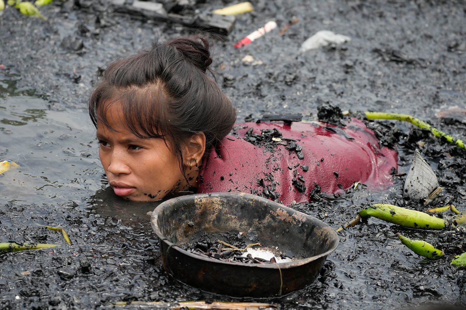  A woman searches for nails and other metal scraps from remains of burned houses that were gutted during a fire at a poor bayside village in the district of Tondo, Manila, Philippines on Friday, May 20, 2022.  (AP Photo/Aaron Favila) 