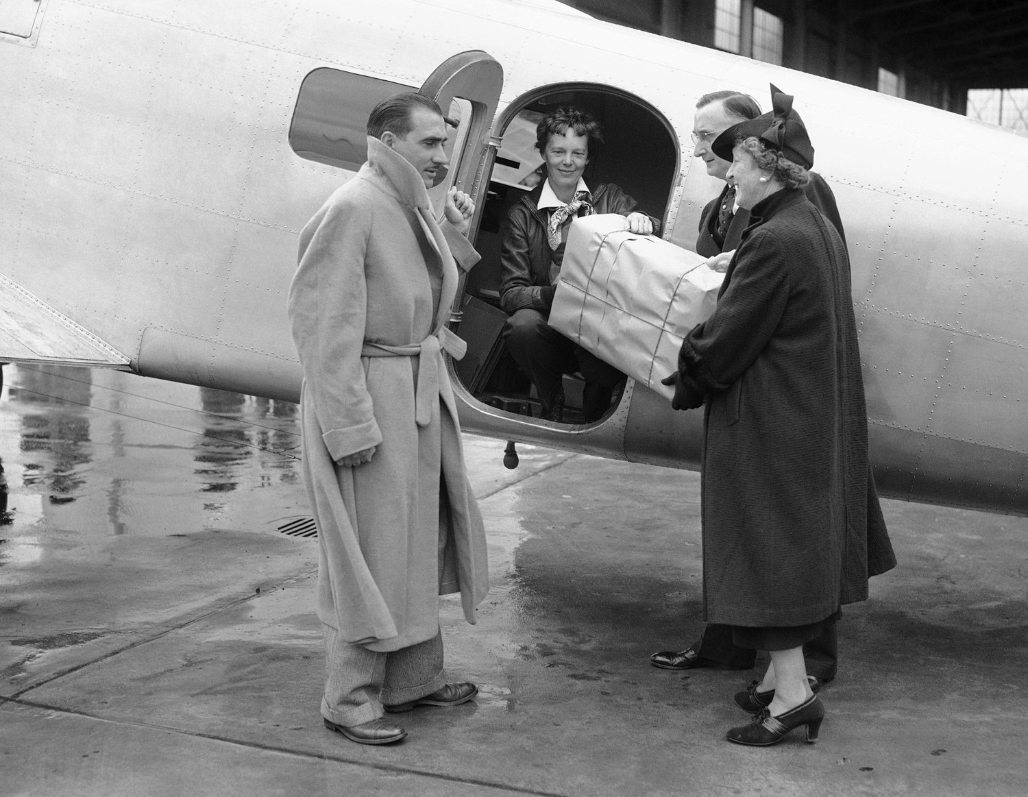  Receiving a box to place aboard her airplane shortly before she took off for Honolulu is Amelia Earhart, Mach 18, 1937, Oakland., Calif. Honolulu was the first stop on her round-the world flight. Left is Paul Mantz, co-pilot as far as Honolulu. Post