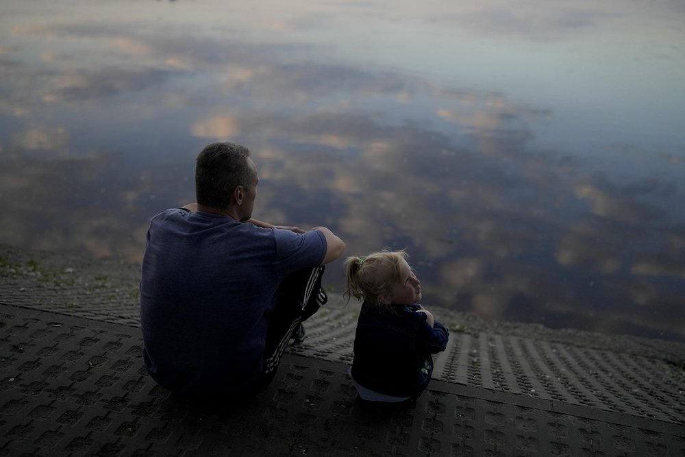  A man sits with a child at Natalka Park in Kyiv, Ukraine, Tuesday, June 7, 2022. (AP Photo/Natacha Pisarenko) 