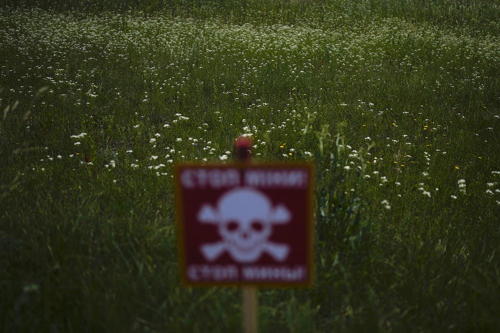  A danger sign warning about land mines is posted in a field blanketed with wildflowers near Lypivka, on the outskirts of Kyiv, Ukraine, Tuesday, June 14, 2022. Russia’s invasion of Ukraine is spreading a deadly litter of mines, bombs and other explo