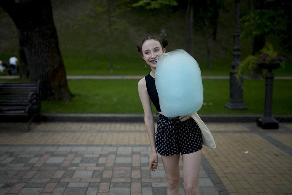  A young woman smiles while holding a bundle of cotton candy at a square in Kyiv, Ukraine, Friday, June 10, 2022. (AP Photo/Natacha Pisarenko) 