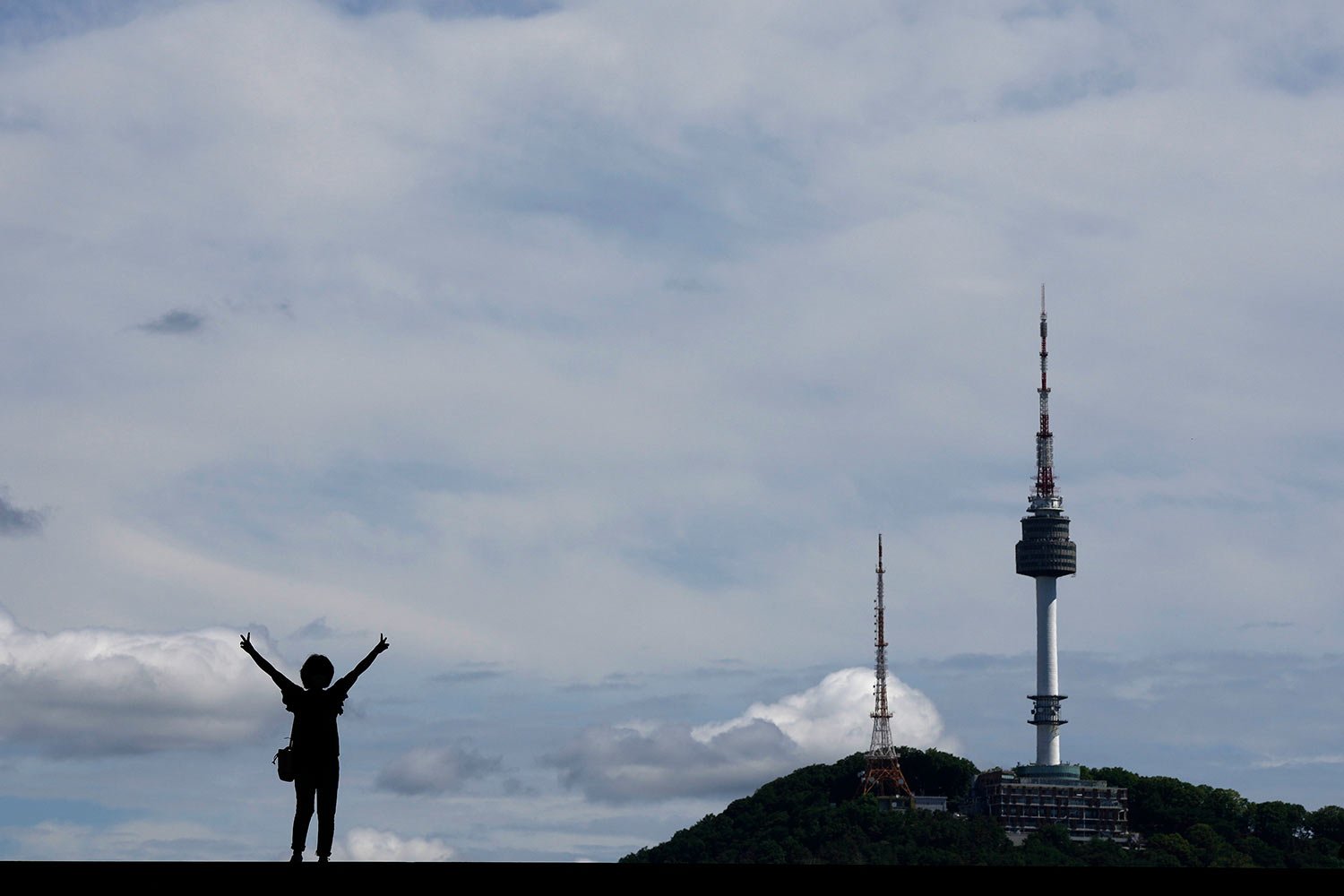  A woman poses for a souvenir photo as she is silhouetted against the sky and the iconic N Seoul Tower at the National Museum of Korea in Seoul, South Korea, Tuesday, June 7, 2022. (AP Photo/Lee Jin-man) 