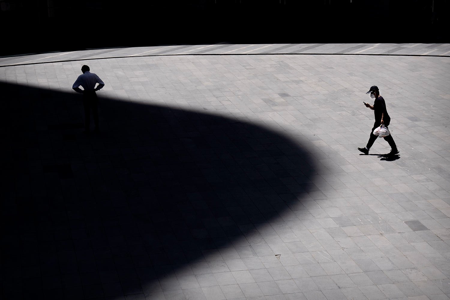  A delivery driver wearing a face mask walks through a plaza at a shopping and office complex in Beijing, Wednesday, June 1, 2022. (AP Photo/Mark Schiefelbein) 