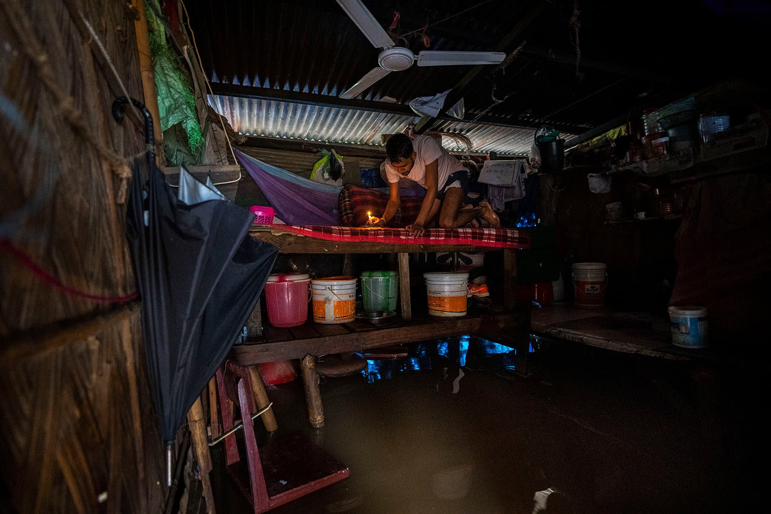  A man holds a candle and prepares to eat  a meal in his waterlogged house after continuous rainfall in Gauhati, India, Wednesday, June 15, 2022. (AP Photo/Anupam Nath) 