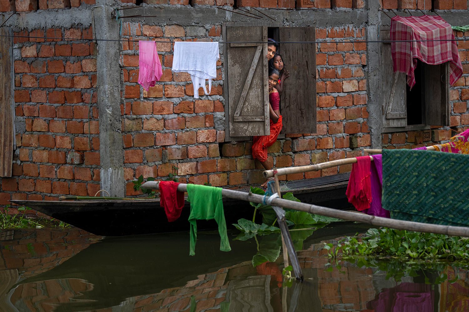  People look out from the window of their flooded house in Tarabari village, in the northeastern Indian state of Assam, Monday, June 20, 2022.  (AP Photo/Anupam Nath) 