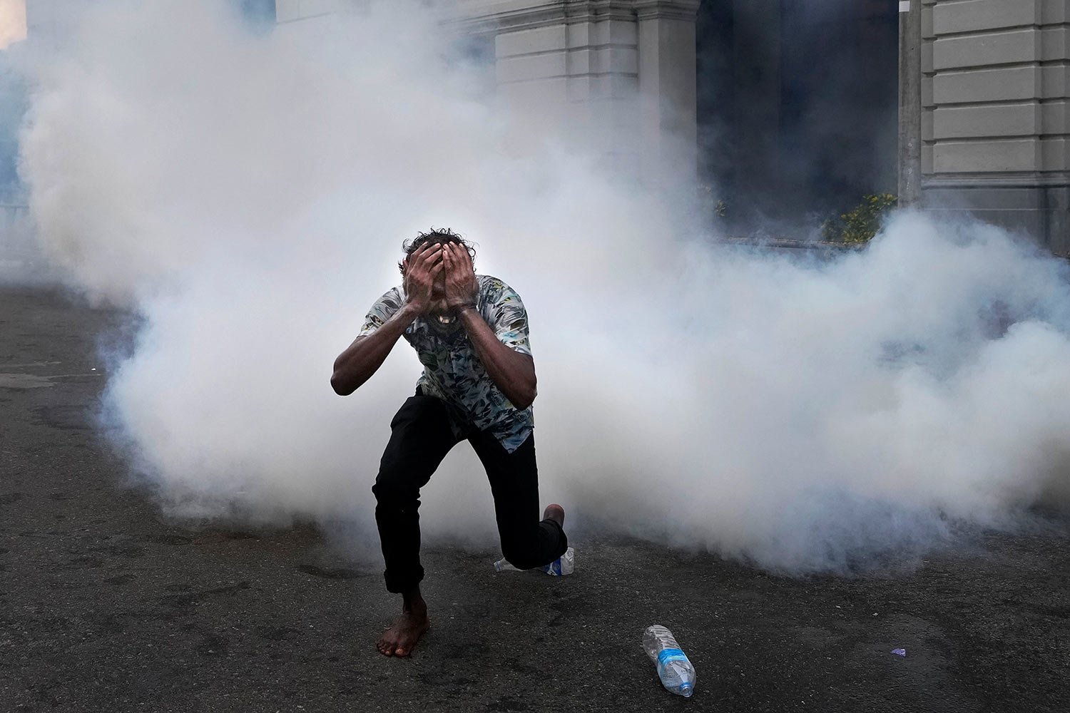  A man runs  from tear gas fired by police to disperse anti-government protesters near police headquarters in Colombo, Sri Lanka, Thursday, June 9, 2022. (AP Photo/Eranga Jayawardena) 