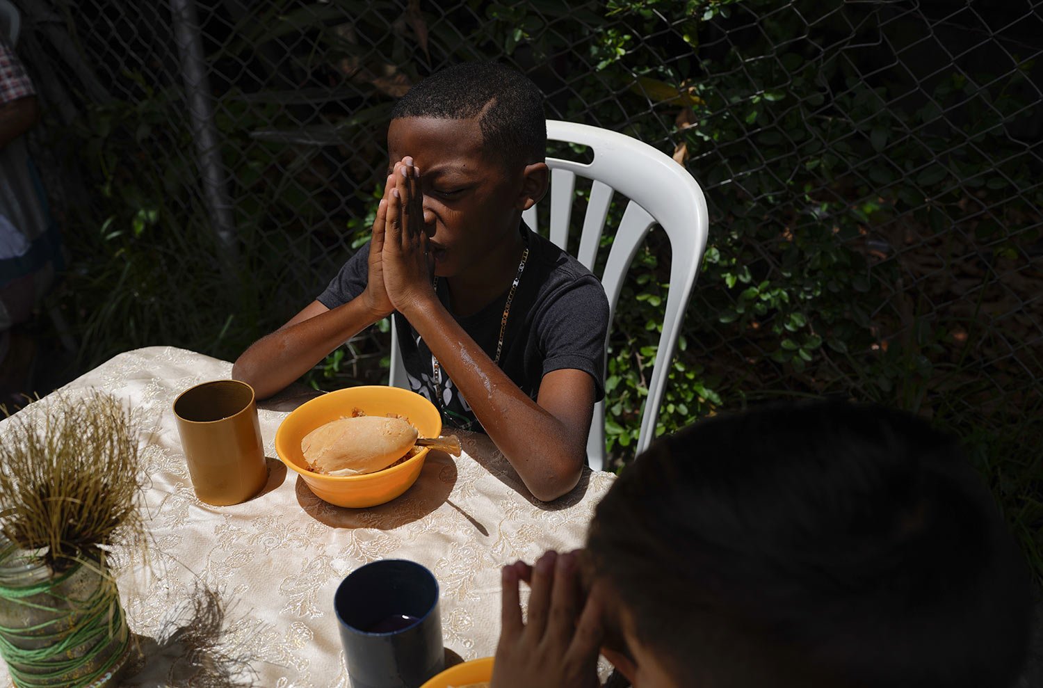  Boys say a prayer before digging into their free lunch donated by the New Birth's Christian church, in the Catia neighborhood of Caracas, Venezuela, Wednesday, June 8, 2022. (AP Photo/Ariana Cubillos) 