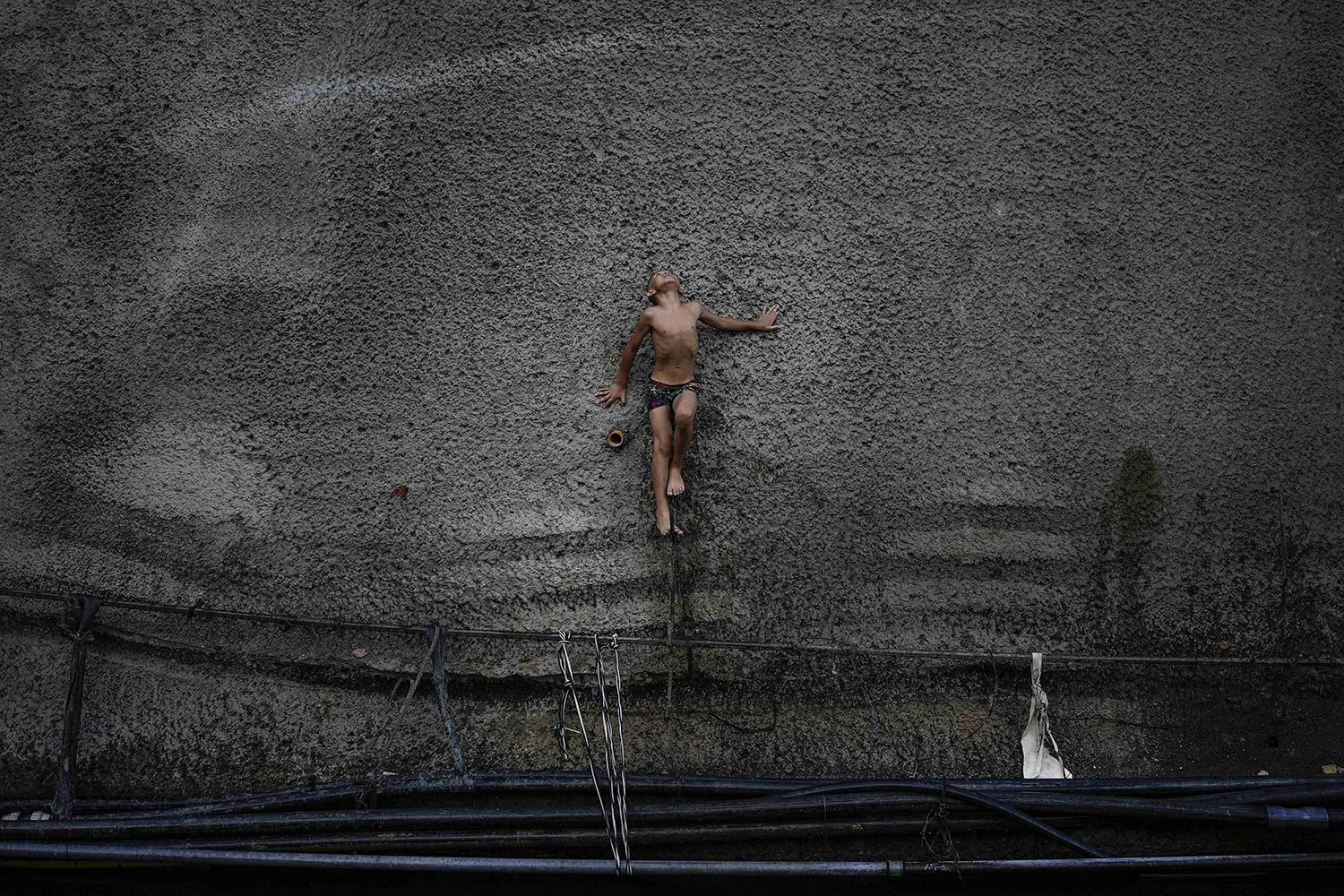  A boy balances on a piece of rebar as he prepares to jump into a ditch that drains water from an abandoned highway tunnel in Caracas, Venezuela, Saturday, June 4, 2022. (AP Photo/Matias Delacroix) 