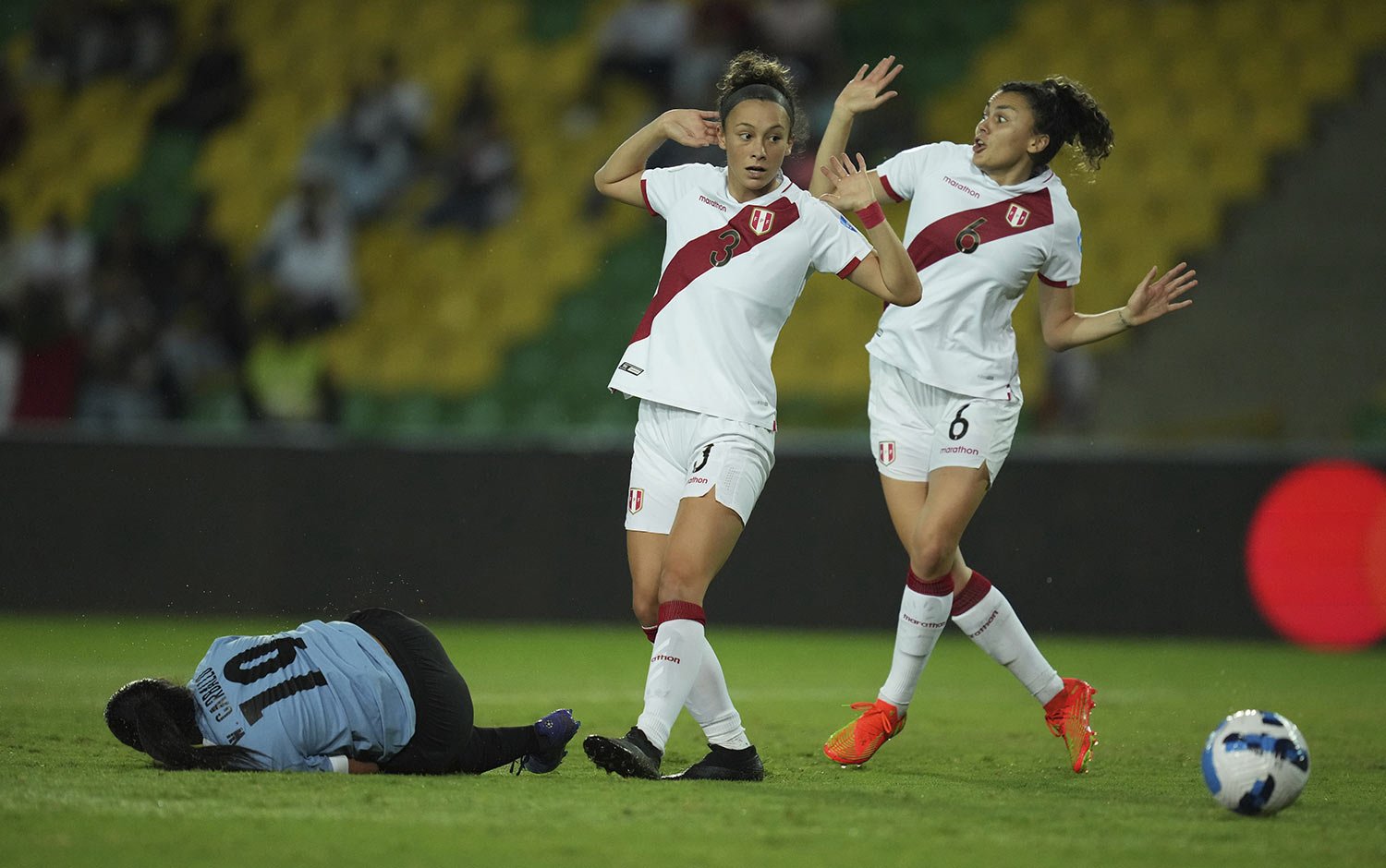  Peru's Grace Canigna, center, and her teammate Claudia Canigna react as Uruguay's Wendy Carballo lies on the field after a foul during a Women's Copa America soccer match in Armenia, Colombia, Monday, July 18, 2022. (AP Photo/Dolores Ochoa) 