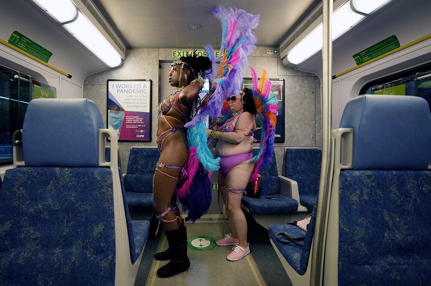  Missy, right, adjusts her friend Sasha’s costume as they ride the train to the Caribbean Carnival parade in Toronto, Canada, Saturday, July 30, 2022. (AP Photo/Kamran Jebreili) 