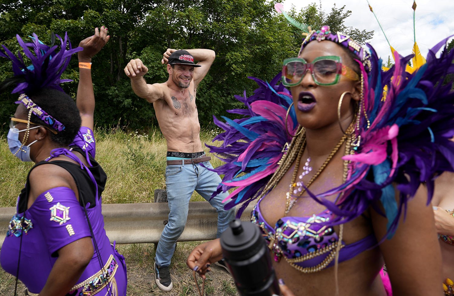  A homeless man dances as Caribbean Carnival participants parade past in Toronto, Canada, Saturday, July 30, 2022. (AP Photo/Kamran Jebreili) 